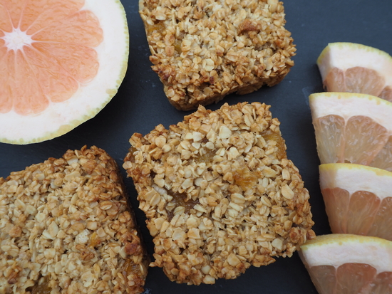 Close up of three pineapple and grapefruit flapjacks with half a grapefruit and 4 slices of grapefruit to the side
