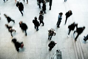blurry photo of workers doing the daiily commute on a train station platform