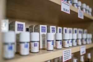 Rows of small remedy bottles with price tags on wooden shop shelves